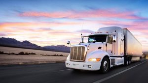 A semi-truck hauling freight on a highway at sunset, symbolizing the vital role of funding in keeping trucking operations smooth and on schedule