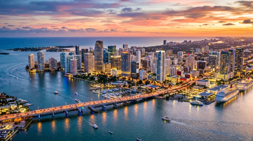 Aerial view of Miami's downtown financial district with modern skyscrapers reflecting on Biscayne Bay at sunset